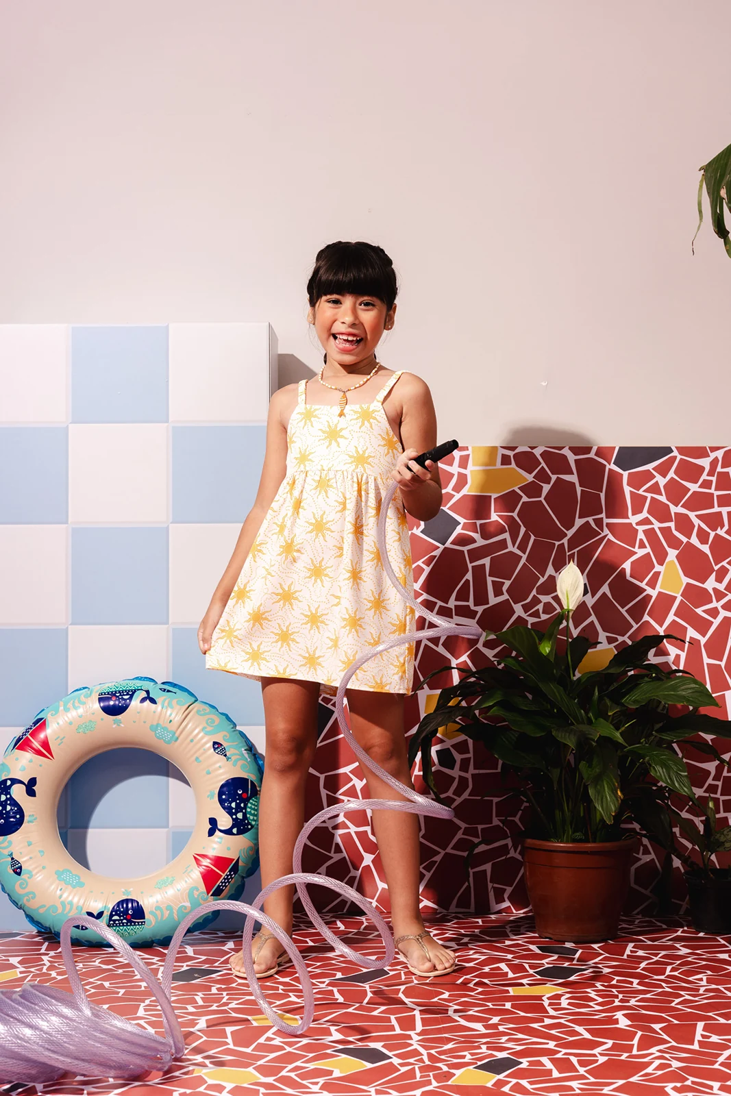 Vestido infantil com estampa de sol fotografado em cenário de verão — Lojas Objetiva